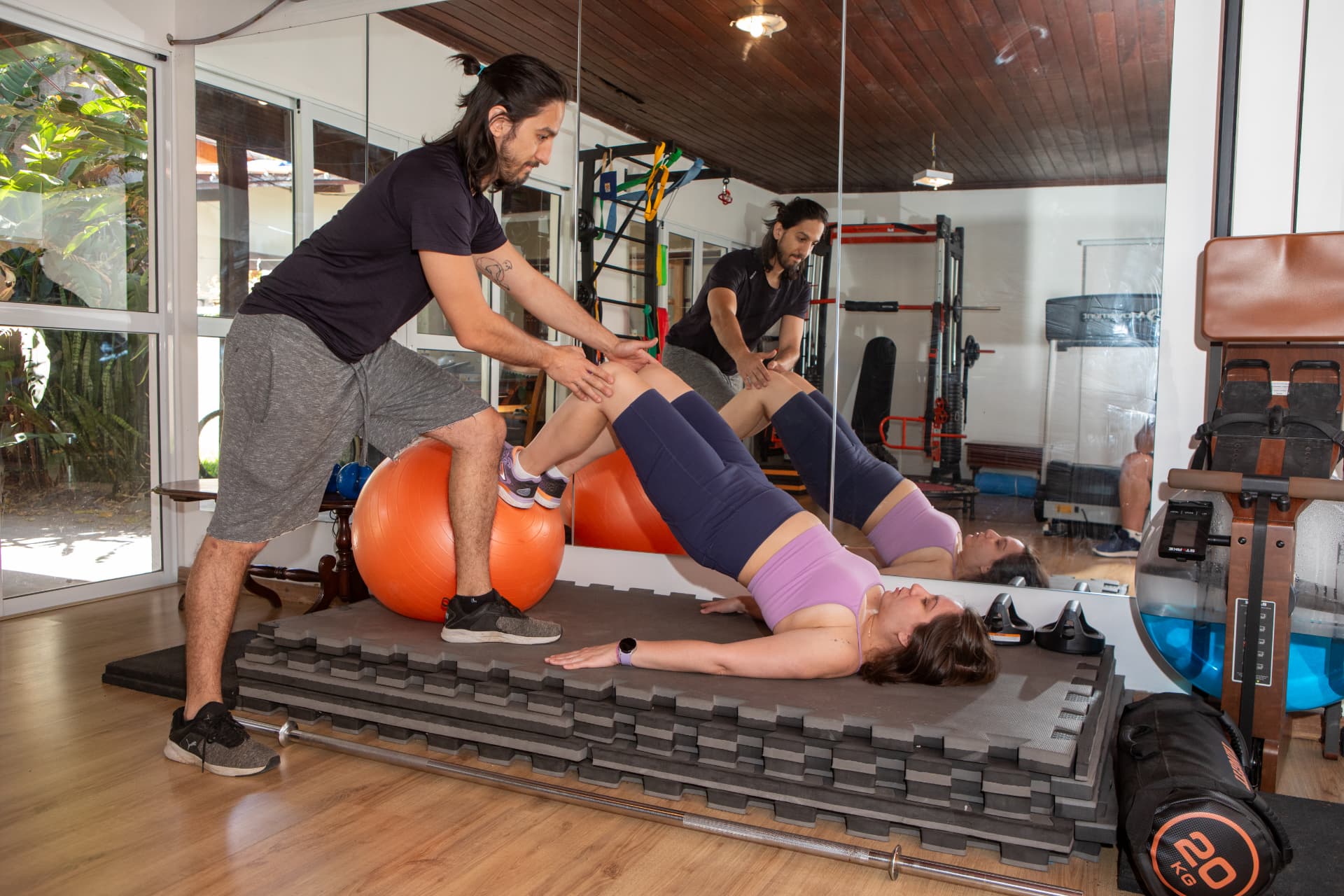 Exercício de ponte com bola suíça assistido pelo fisioterapeuta